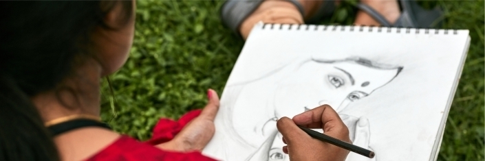 A young woman drawing a pencil sketch of a woman and her infant