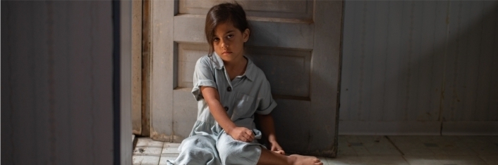 une fille au plancher d'une salle vide avec une expression triste