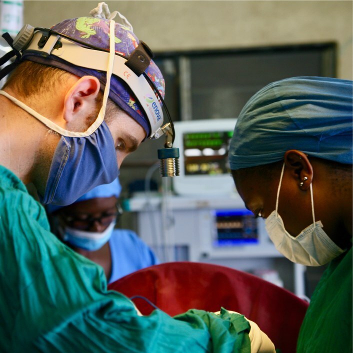 Surgeon working on patient with a nurse assisting him.