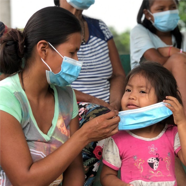 Colombia mother helping her toddler put a medical face mask on