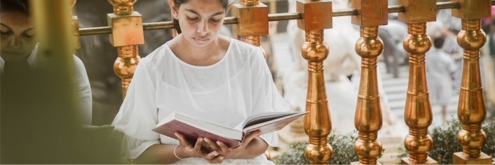 Young girl wearing a white top reading a book