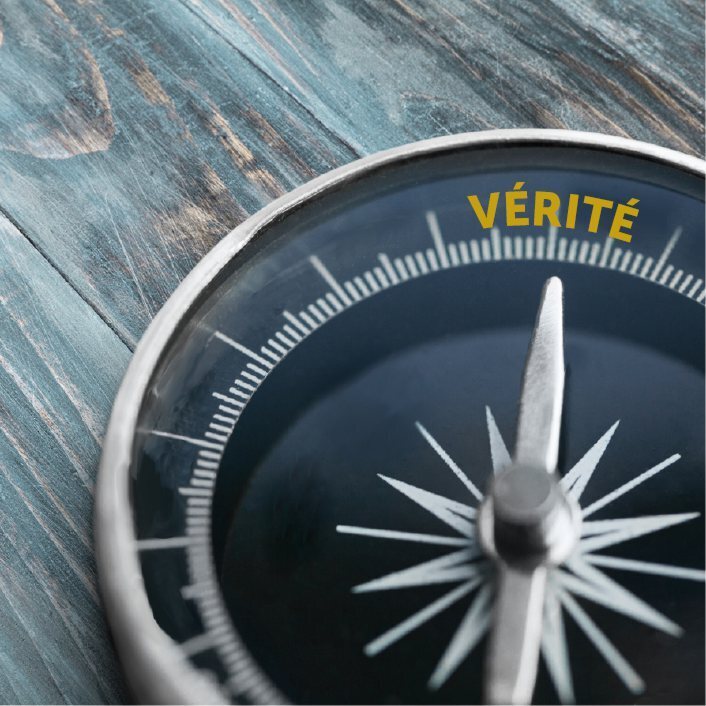 A wooden table with a compass sitting on top pointing to the word "TRUTH".