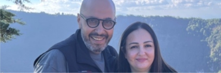 Husband and wife posing with mountains in background